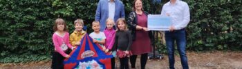Scheckübergabe mit fünf Kindern, die ein Zirkuszelt halten. Dahiner Herr Nowak, FRau Wiechmann und Herr Schrumpf-Harnisch
